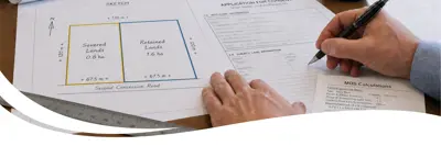 A person writing and drawing descriptions for severance and land-use documents.