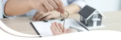 Image of a person at a desk with a document that they signed being provided a house key.
