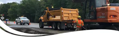 Image of a County truck and people working on the road.