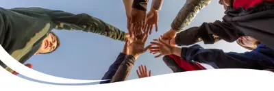 Image of a group of people each putting their hand in the middle of the group