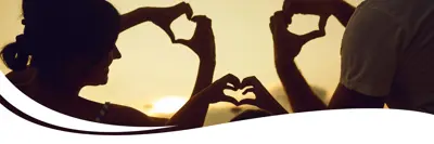 Image of people with hands raised making the shape of a heart with their hands.