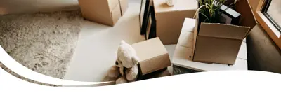Image of the inside of a room with moving boxes and a teddy bear.