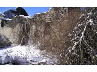 Snow-covered stone walls of an old dilapidated stone farmhouse